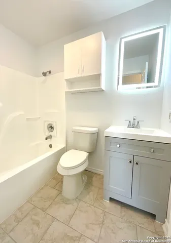 a bathroom with a toilet a sink a mirror a bathtub and vanity