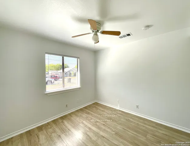 an empty room with wooden floor cabinet and windows