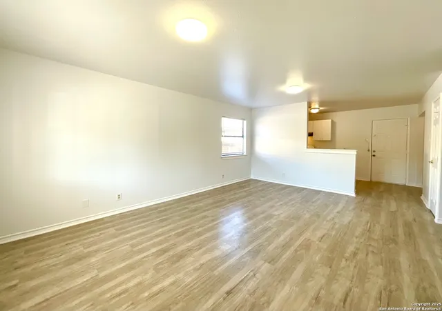 a view of empty room with wooden floor and window