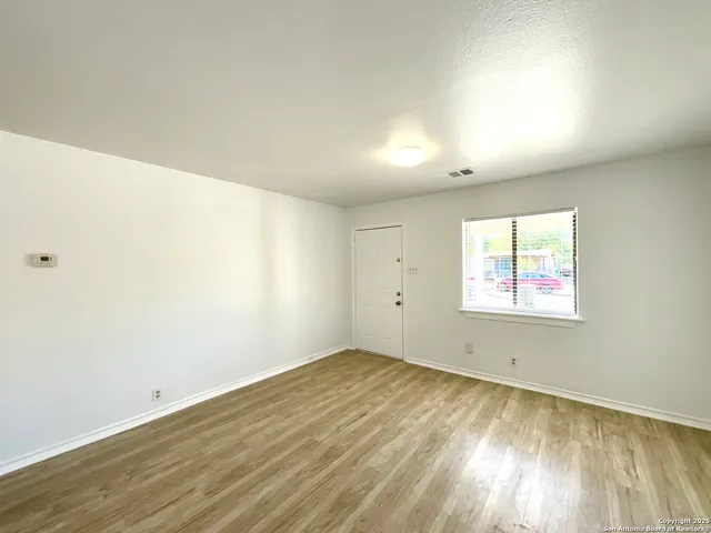 an empty room with wooden floor and windows