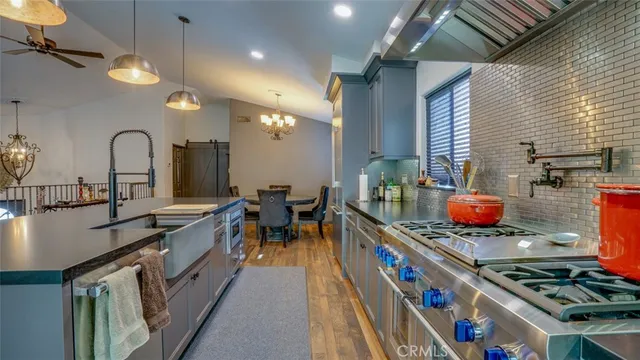 a kitchen with stainless steel appliances granite countertop a sink a stove and a wooden floors