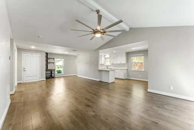 a view of an empty room with window and wooden floor