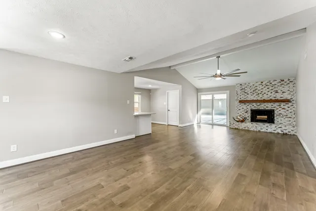 an empty room with wooden floor fireplace and windows
