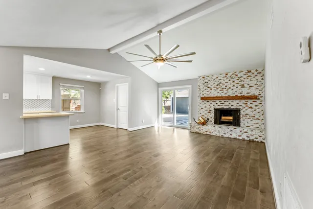an empty room with wooden floor a fireplace and windows