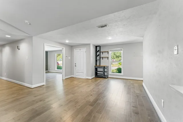 an empty room with wooden floor and windows