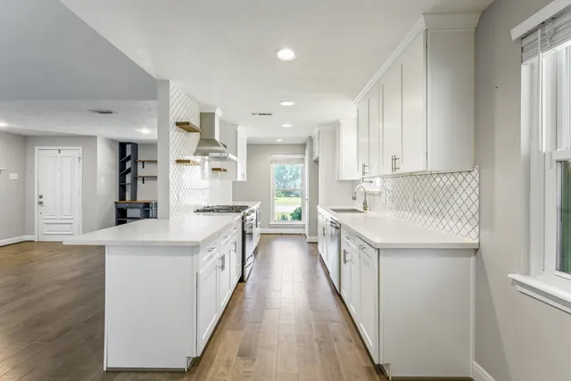 a large kitchen with stainless steel appliances lots of counter space and wooden floor