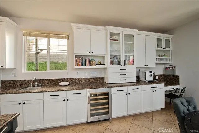 a kitchen with granite countertop a sink white cabinets and white stainless steel appliances