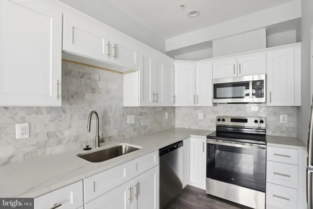 a kitchen with stainless steel appliances granite countertop white cabinets a stove a sink and dishwasher
