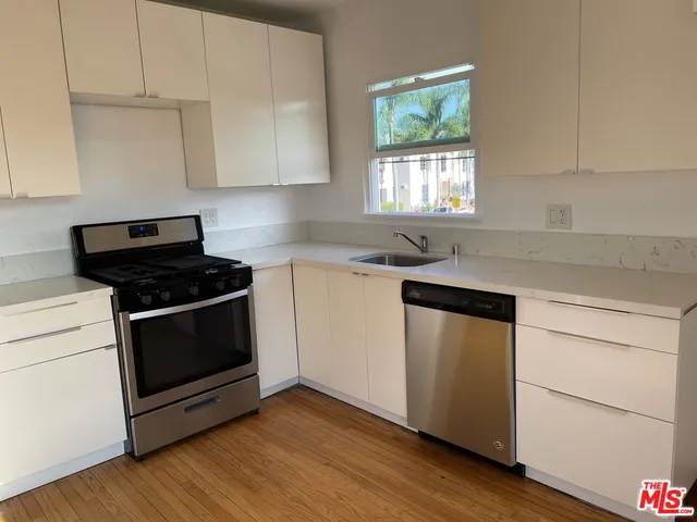 a kitchen with granite countertop white cabinets appliances and wooden floor