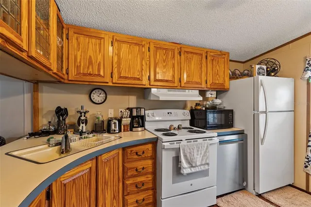 a kitchen with stainless steel appliances granite countertop a refrigerator a stove and a sink with dishwasher