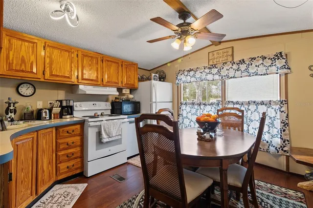 a kitchen with stainless steel appliances granite countertop a sink a stove a dining table and chairs with wooden floor