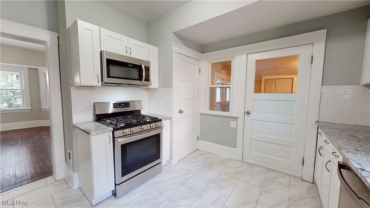 3174 Oak Road Cleveland, OH 44118 - Photo 11 of 33 Kitchen featuring appliances with stainless steel finishes, light marble finish flooring, light stone countertops, and white cabinets