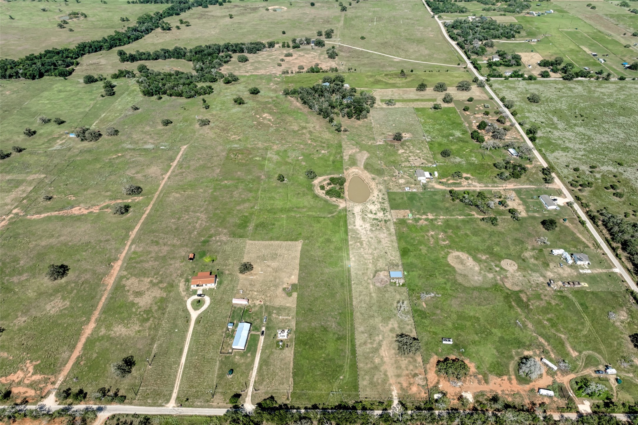 5309 Tenney Creek Road Luling, TX 78648 - Photo 13 of 23 Vast acreage features a private pond and multiple outbuildings across verdant fields.