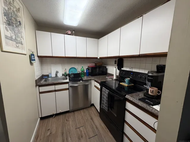 a kitchen with granite countertop white cabinets and stainless steel appliances