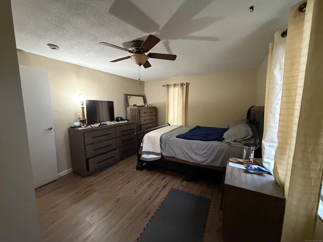 a bedroom with a bed wooden floor and ceiling fan