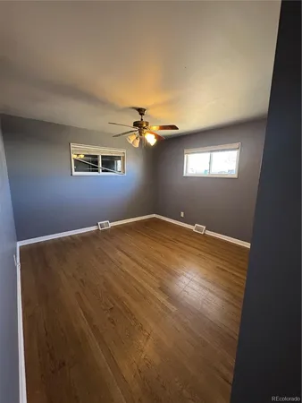 a view of an empty room with a chandelier fan and a window