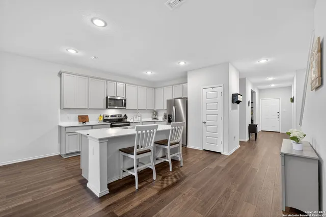 a kitchen with stainless steel appliances a dining table chairs microwave and refrigerator