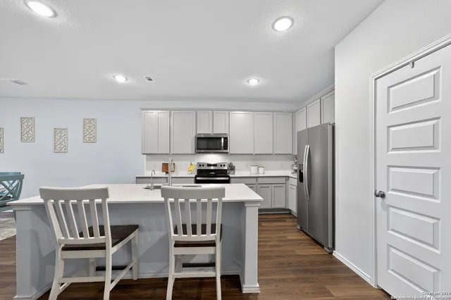 a kitchen with a refrigerator a stove top oven and white cabinets