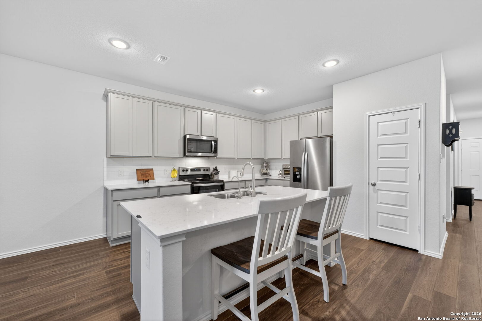 132 Bella Rosa Trail Cibolo, TX 78108 - Photo 18 of 49 a kitchen with stainless steel appliances a stove a sink dishwasher a refrigerator with white cabinets and wooden floor