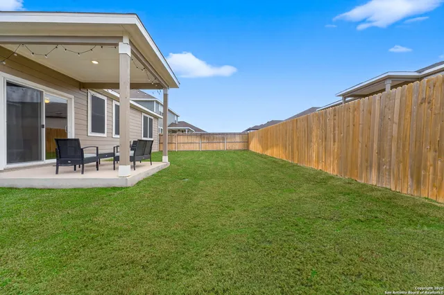 a view of a patio with table and chairs with plants and wooden fence