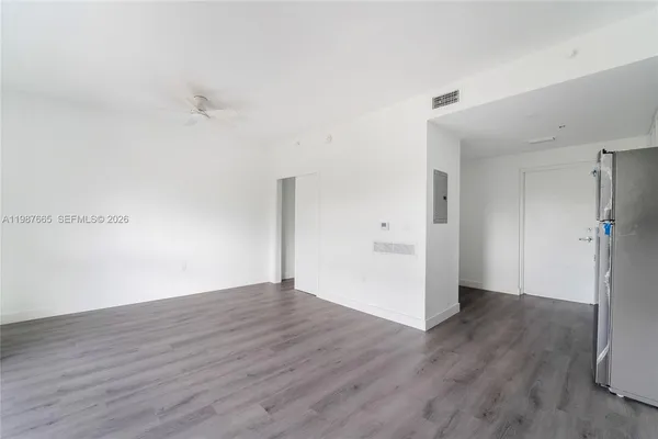 an empty room with wooden floor and a ceiling fan