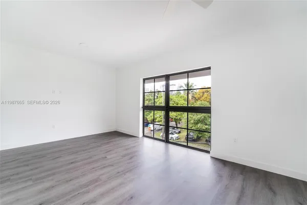 an empty room with wooden floor and windows