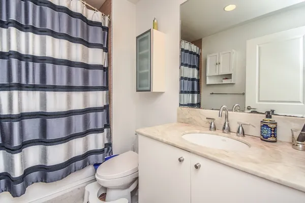 a bathroom with a granite countertop sink and a toilet