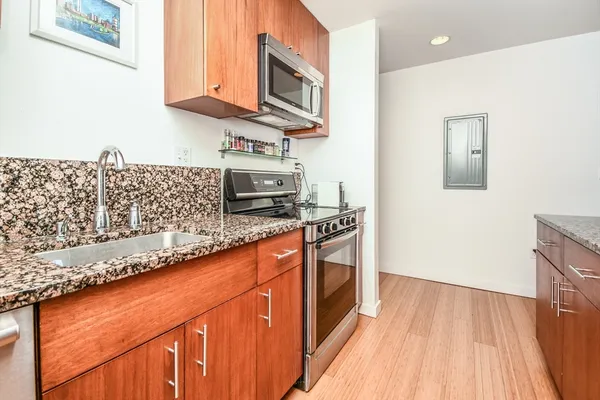 a kitchen with stainless steel appliances granite countertop a stove a sink and a microwave oven with wooden floor