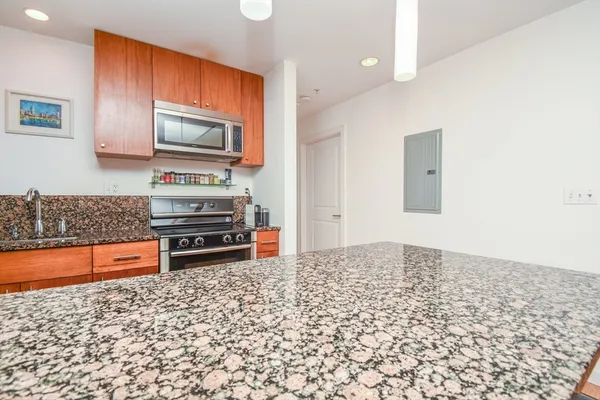 a kitchen with granite countertop a stove a sink and a microwave