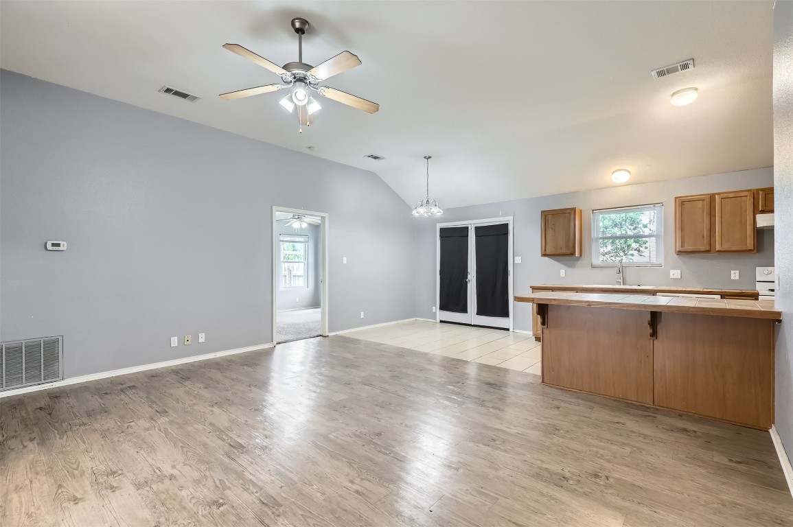 a view of an empty room with kitchen and a window