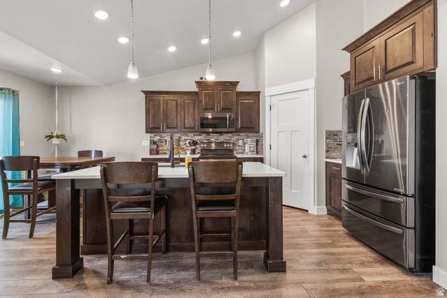 463 South Trejo Ridge Road Grantsville, UT 84029 - Photo 6 of 22 Kitchen featuring a central island with white countertop, dark wood-finish cabinetry, stainless steel appliances, and a tiled backsplash