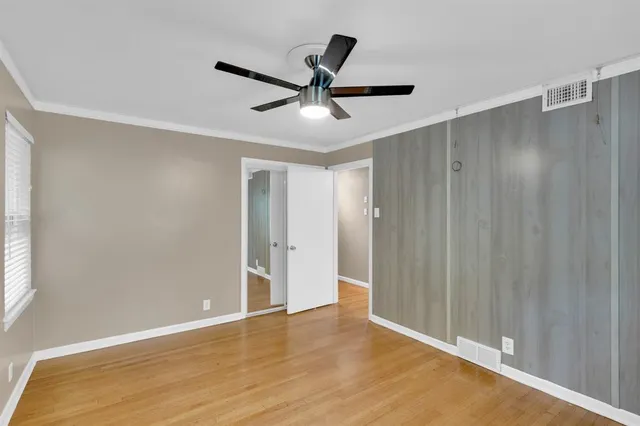 a view of empty room with wooden floor and fan