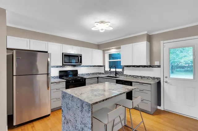 a kitchen with a refrigerator a stove a microwave and island with wooden floor