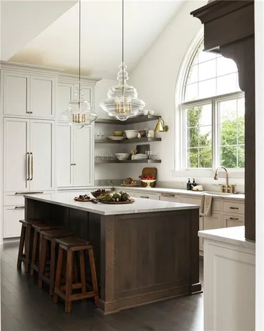 a kitchen with kitchen island a stove a sink a window and cabinets