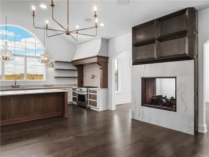 a living room with stainless steel appliances kitchen island a fireplace and wooden floor