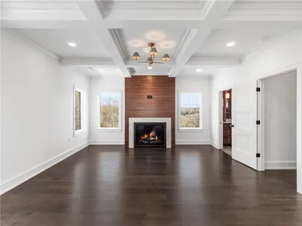 an empty room with wooden floor fireplace and windows