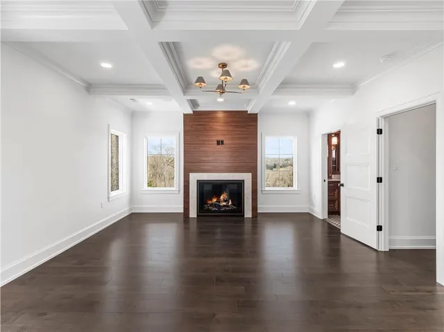an empty room with wooden floor fireplace and windows