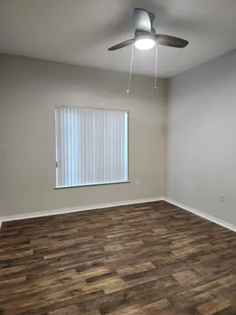 a view of an empty room with window and wooden floor