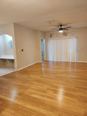 a view of empty room with wooden floor and fan