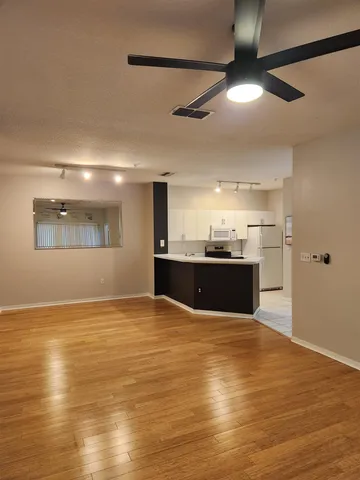 a view of kitchen and empty room with wooden floor