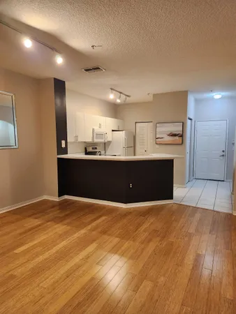 a view of kitchen and empty room with wooden floor