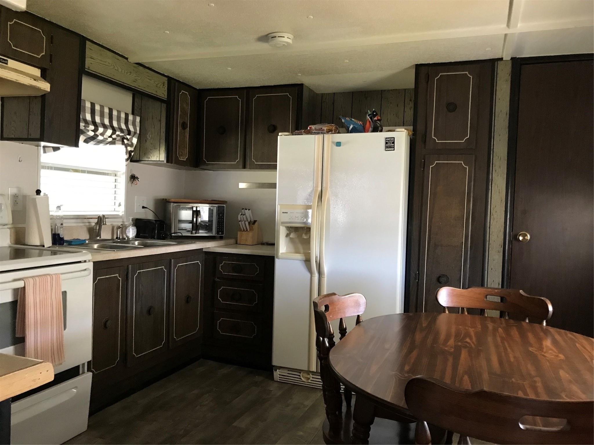 1379 Chobee Street Okeechobee, FL 34974 - Photo 6 of 13 a kitchen with stainless steel appliances a refrigerator a sink a stove a dining table and chairs