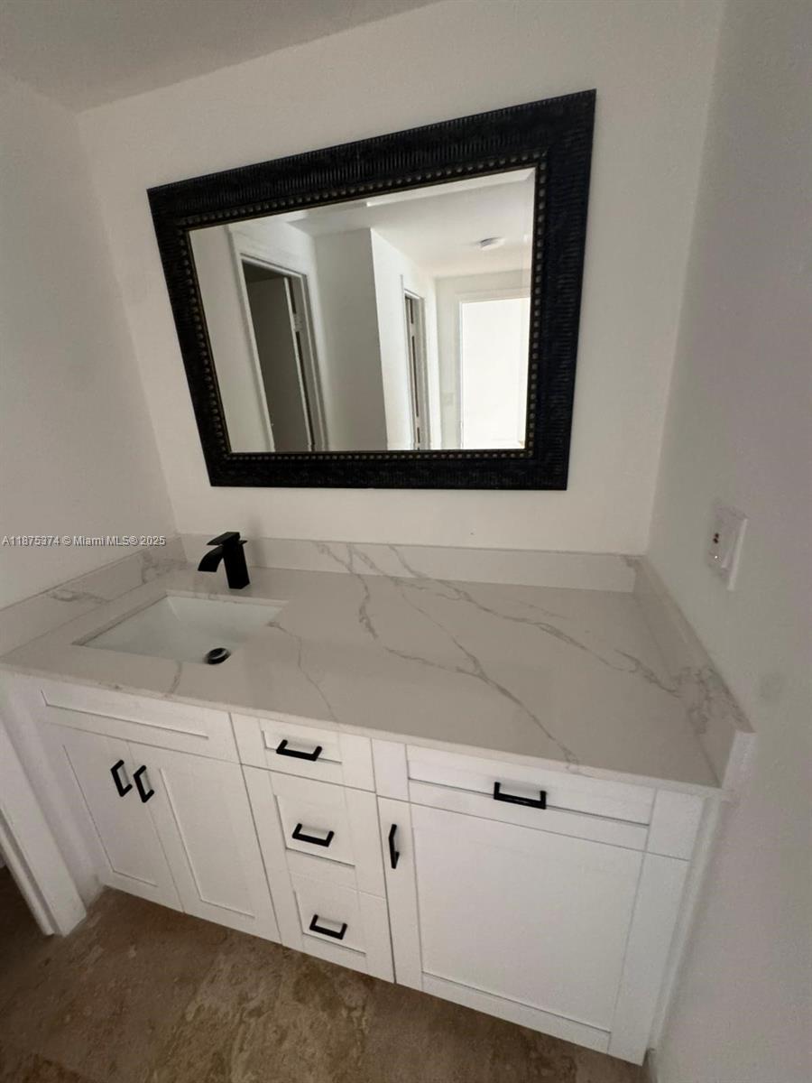 500 Bayview Drive, Unit 230 Sunny Isles Beach, FL 33160 - Photo 28 of 48 a bathroom with white cabinets sink and mirror