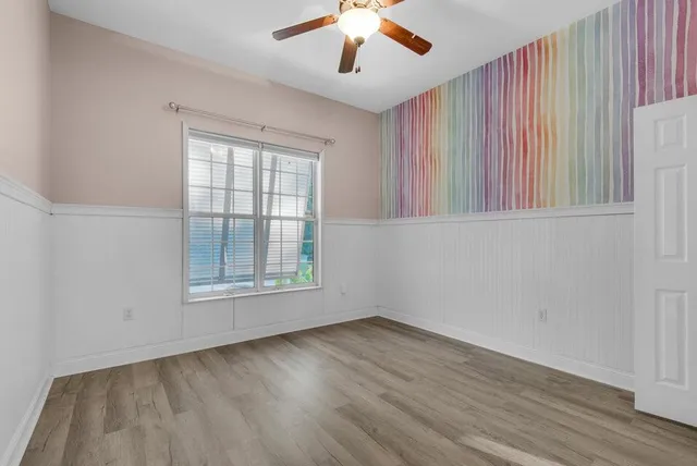 a view of an empty room with wooden floor and a window