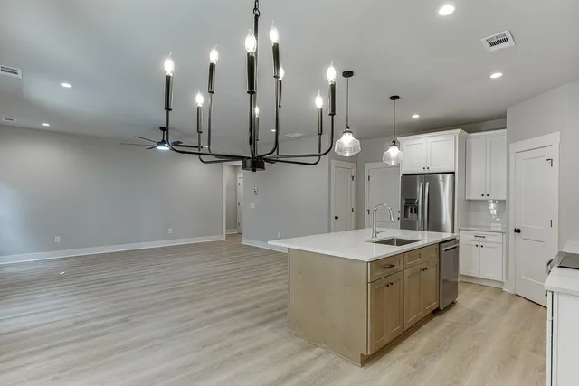 a kitchen with a sink chandelier and refrigerator