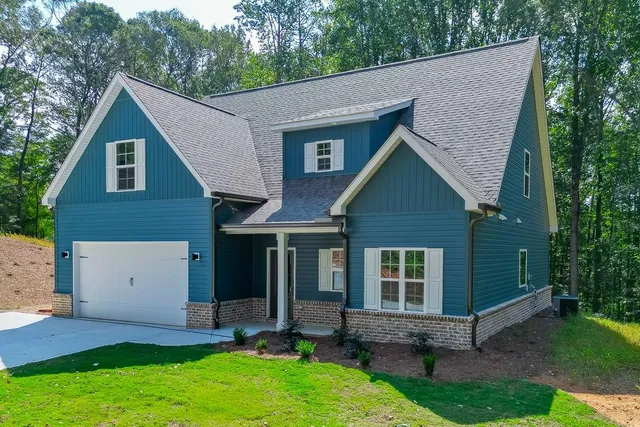 a view of a house with a yard plants and large tree