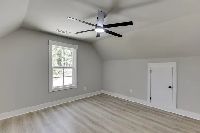 an empty room with wooden floor closet and windows