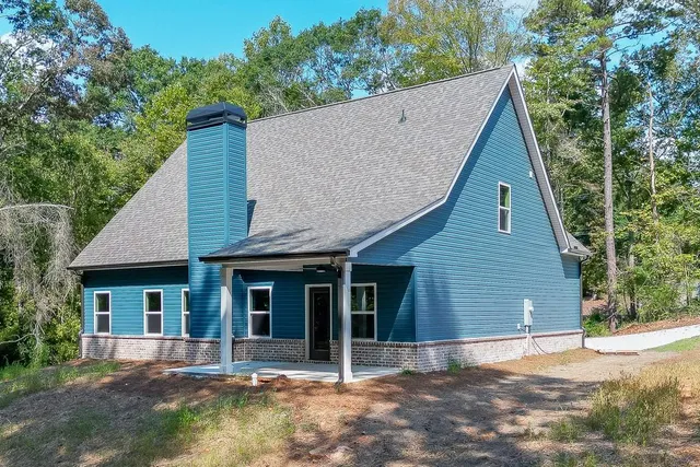 a view of a house with a yard plants and large tree