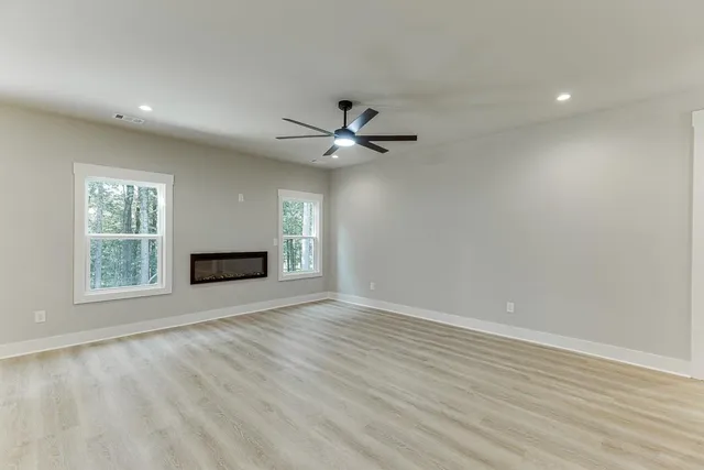 an empty room with ceiling fan and windows