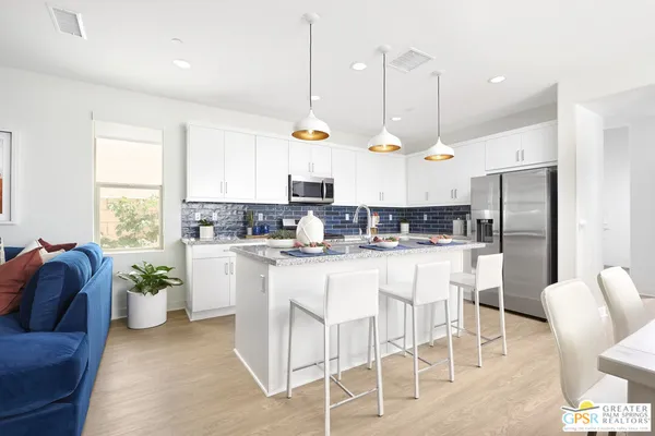a kitchen with stainless steel appliances kitchen island granite countertop a refrigerator a stove a sink dishwasher and white cabinets with wooden floor